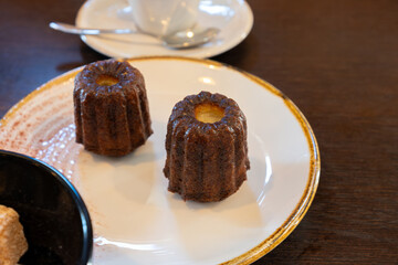 Canele, French pastry flavored with rum and vanilla, specialty of Bordeaux region, France, served with cup of black coffie in French restaurant