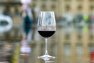 Tasting of Bordeaux blended red wine with wine city Bordeaux on background, left bank of Gironde Estuary, France. Glass of red French wine.