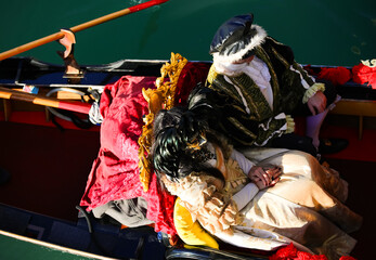 Venice, VE, Italy - February 13, 2024: married couple with historical costumes on the gondola during the carnival - obrazy, fototapety, plakaty