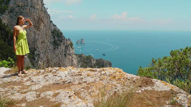 A person surveys the horizon from a high cliff. The sea expanse dotted with ships and boats, suggesting the vastness and beauty of this maritime vista. Capri, Italy.