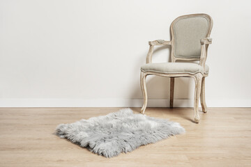 an unvarnished light wooden armchair with a gray upholstered seat, a gray shag rug in a room with...