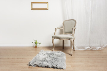 an unvarnished light wooden armchair with a gray upholstered seat, a gray rug in a room with white...