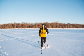 Man training on skis, running on snow field, solo walk in the fresh air.