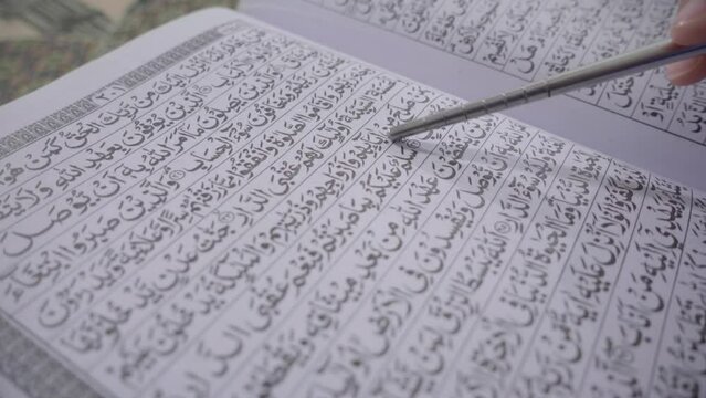 Reading Quran in the mosque with reading stick. Reading quran and pointing to word of allah