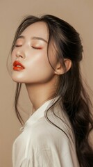 Close-up of a serene Asian young woman with closed eyes, showcasing vibrant lipstick and subtle makeup