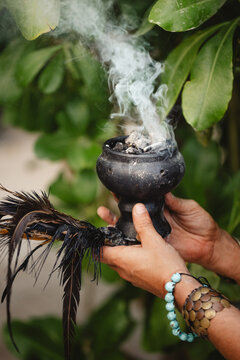 Copal sostenido por una mano con plumas, para rituales y limpieza energ&eacute;tica en Tulum M&eacute;xico