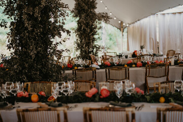 
Detalle de mesa para comer en un banquete de bodas. Mesa alargada con tonos beige, verdes, naranjas y rosas. Foto vertical con fuga en la parte superior.