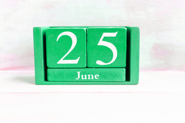 June 25. green cube calendar with month date isolated on wooden background.