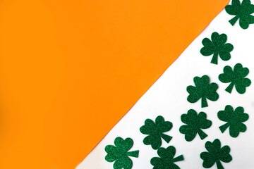 Happy St. Patricks Day. Shamrocks pattern on white and orange background. Patrick Day symbols on...