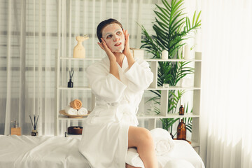 Fototapeta na wymiar Serene modern daylight ambiance of spa salon, woman customer posing and indulges in rejuvenating with facial skincare mask. Facial skin treatment and beauty cosmetology procedure for face. Quiescent