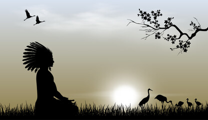 American Indian against a sunset background. An Indian sits on the grass against the background of the sky and the sun. Birds are visible in the distance. Tree branch