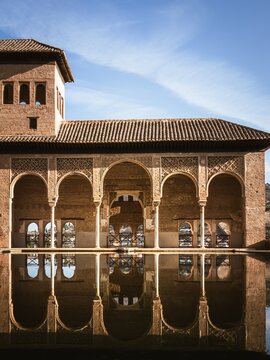 Buildings of the Alhambra Palaces in the El Partal part, reflection in the water pool, palm trees
