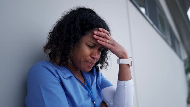 Young female doctor feeling overwhelmed at work, sitting on bench, smoking cigarette. Healthcare workers having stressful job, feeling exhausted. Burnout syndrome for doctors and nurses.