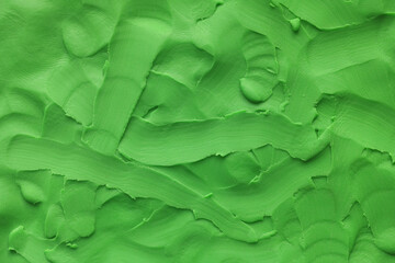 A background texture made out of green play clay. Close up.
