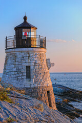 Castle Hill Lighthouse built into the cliff in 1890, during the blue hour just after at sunset, Newport, Rhode Island, USA as summer turns to fall. A scenic autumn landscape, seascape.