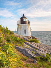 Fototapeta na wymiar A vertical scenic view of Castle Hill Lighthouse, Newport, Rhode Island and the rocky cliffs along Narragansett Bay in the summer.