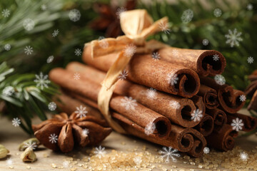 Different spices and fir tree branches on wooden table, closeup. Cinnamon, anise, cardamom