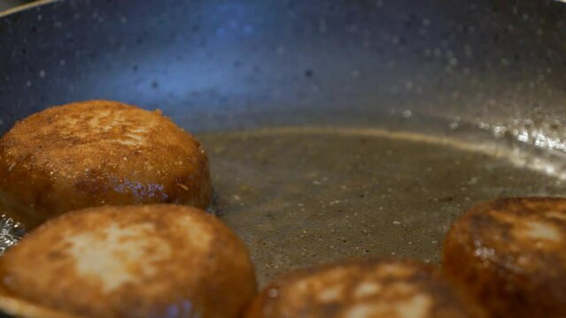 Close-up view of freshly fried Georgian dish Chadi donuts being removed from a boiling pan with a fork and wooden spoon.