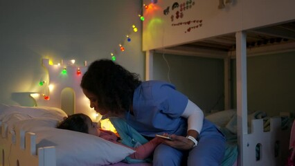 Nurse getting late home from work, stroking sleeping daughters hair. Portrait of beautiful doctor with Christmas hat on head. Working in hospital on Christmas day, Christmas Eve. Female doctor working