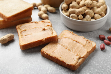 Fototapeta na wymiar Tasty peanut butter sandwiches and peanuts on gray table, closeup