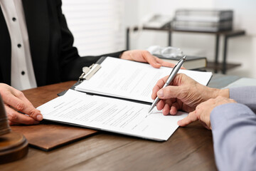 Senior man signing document in lawyer's office, closeup