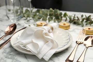 Beautiful place setting with candles and eucalyptus on white marble table
