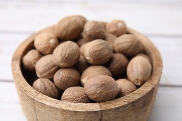 Whole nutmegs in bowl on light table, closeup