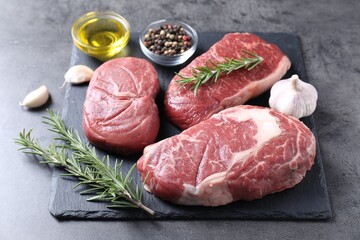 Raw beef steaks, oil and spices on grey background