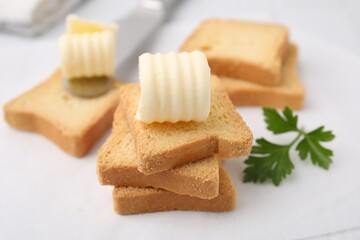 Tasty butter curls, knife and pieces of dry bread on white table, closeup