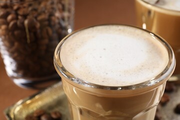 Aromatic coffee with milk in glass on table, closeup
