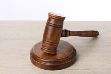 Wooden gavel on light table against white background