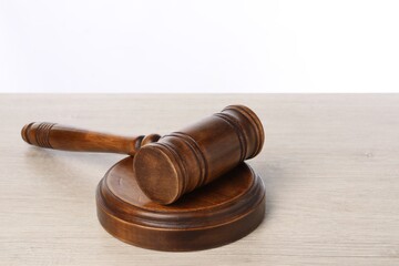 Wooden gavel on light table against white background