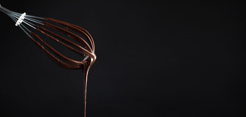 Whisk with yummy chocolate cream on black background, closeup. Banner design with space for text