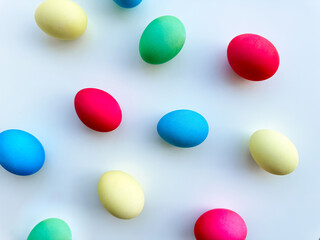 Colorful Easter eggs scattered on white background, flat lay composition for spring holiday celebration and decoration ideas. For Easter holiday promotions, themed party invitations, seasonal blog