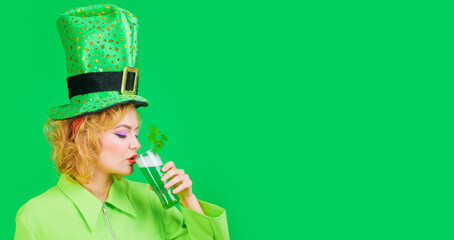 Sexy woman in leprechaun hat with glass of green beer. Beautiful girl in green jacket drinking beer...