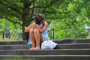 A Hungry Homeless Abandoned Runaway Child Looks For Food And Shelter In Front Of A Church With Her Pet Dog