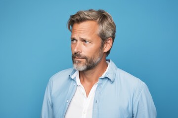 Portrait of handsome mature man in casual shirt on blue background.