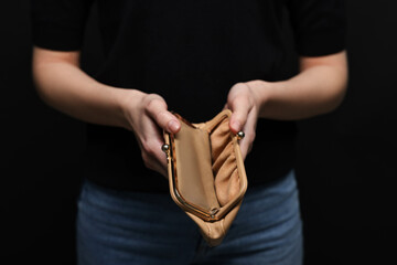 Woman with empty wallet on black background, closeup