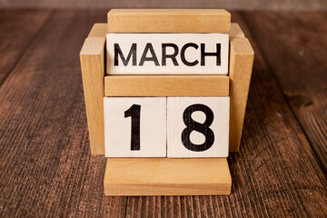 March 18 calendar date text on wooden blocks with blurred park background. Copy space and calendar...