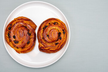 Breakfast in bakery with fresh baked coffee buns sweet pastry with raisins, morning food close up