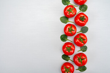 Food ornament, Red ripe tasty Dutch tomatoes and spinach leaves, vegetables background top view close up copy space