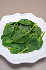 Fresh green baby Spinach leaves, diet and health concept, weight loss, spinach on ceramic plate, copy space