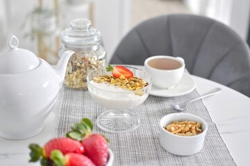 Muesli with yogurt and strawberries, tea.  Healthy breakfast.