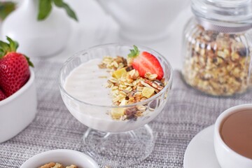 Muesli with yogurt and strawberries, tea.  Healthy breakfast.