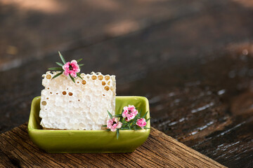 Manuka flowers and honeycomb on natural background.
