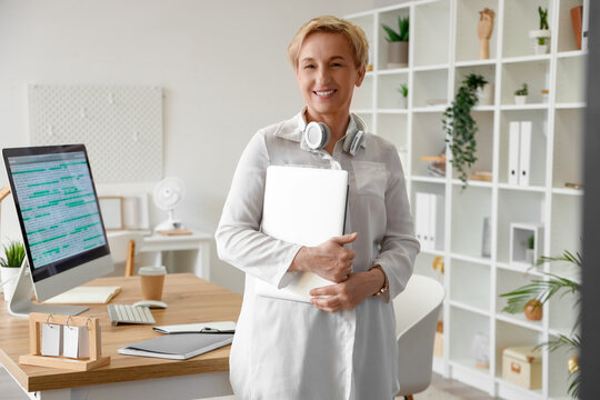 Mature female programmer with laptop in office