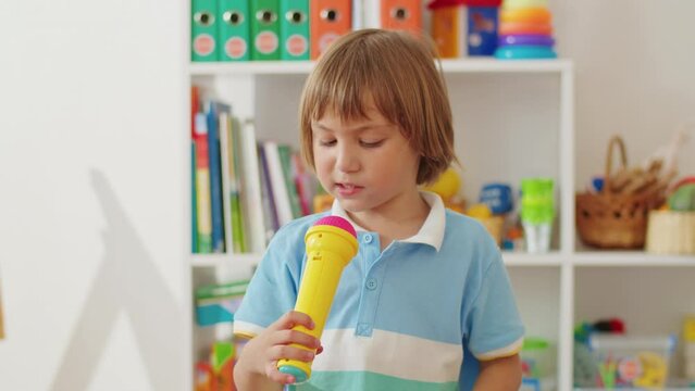 Child playing with a toy microphone in a playroom. Early learning and music education concept for design and print.
