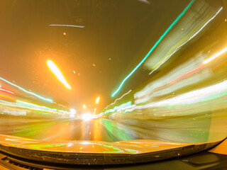 Long exposure of fast car at night traffic lights in the rainy evening. Fog diffusion. City life...