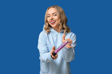Happy young woman with vibrator on blue background