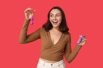 Happy young woman with different sex toys on red background